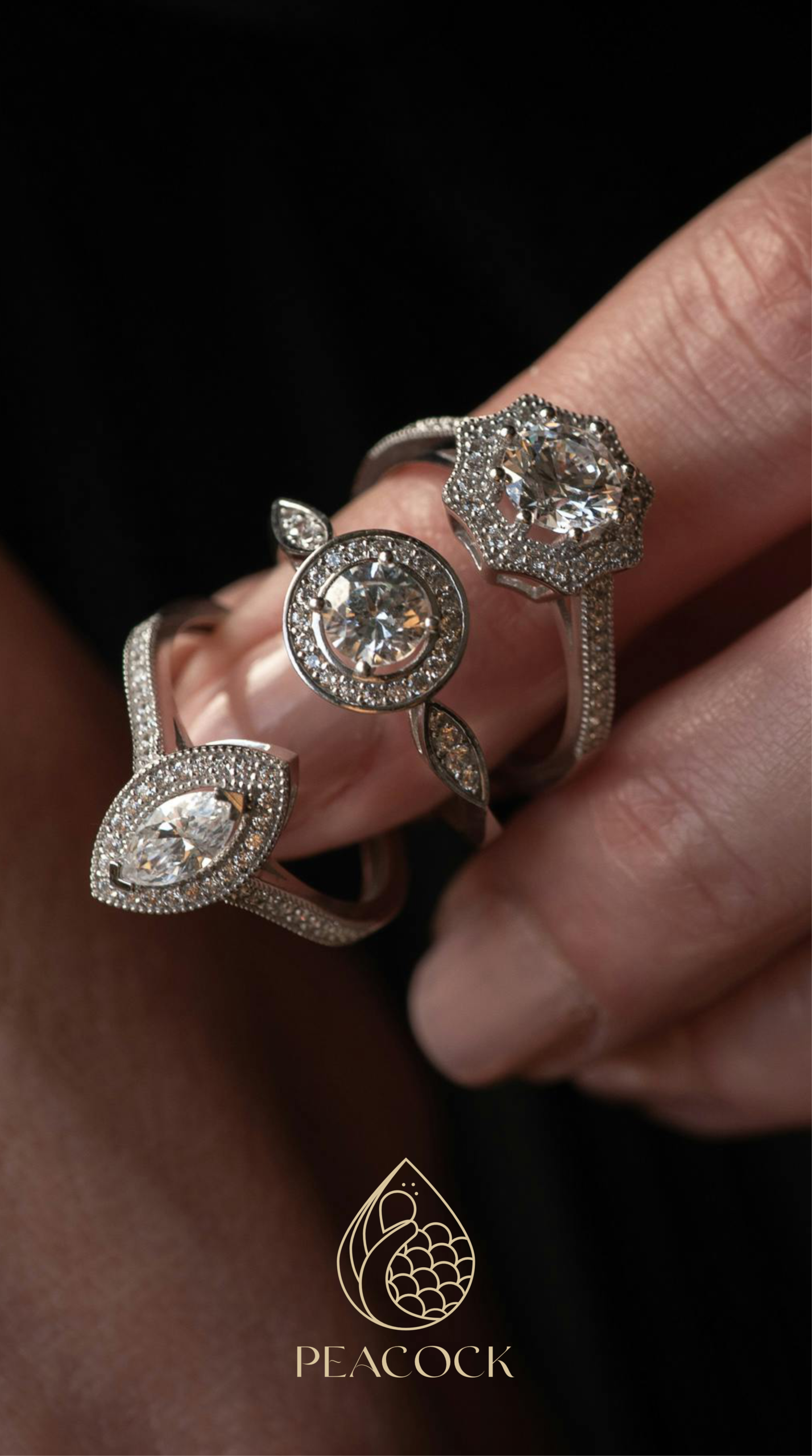 Detalle vertical de tres anillos de diamantes de lujo en una mano, con el logo dorado de Peacock al pie.